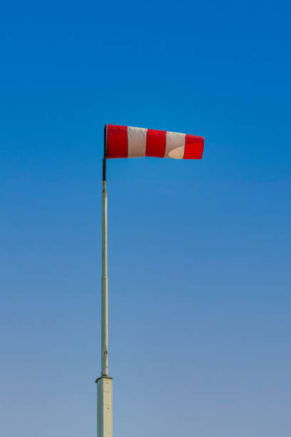istock Red and white colored windsock against a bright blue sky 1308158491
