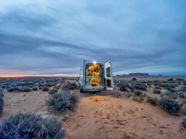 vivere la vita del furgone di conversione nel deserto della monument valley, nello utah e in arizona al tramonto, cloud scape, i monumenti iconici sullo sfondo - arizona desert landscape monument valley foto e immagini stock