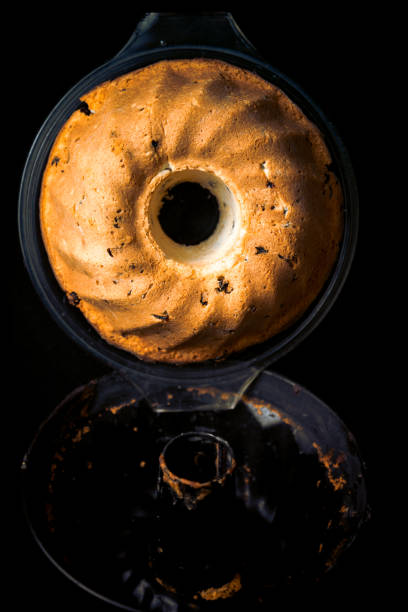 Fresh, tasty, homemade Gugelhupf, ring cake and baking mold, studio shot, dark background.