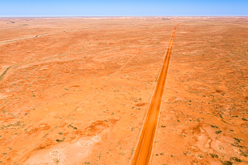 Aerial view of red centre desert region with straight road and Coober Pedy in the far distance, South Australia.