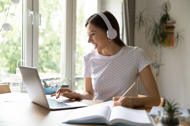 istock Smiling female student in headphones study online on computer 1308167393