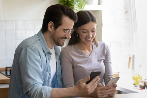 istock Overjoyed millennial couple have fun using cellphones 1308167421