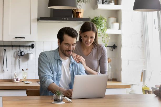 istock Happy couple use laptop in modern home kitchen 1308167427
