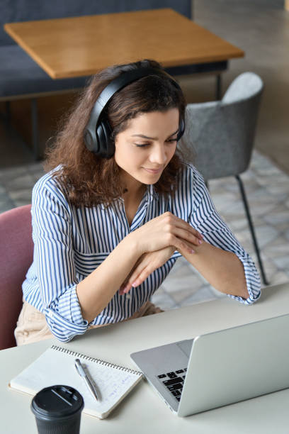 studentessa ispanica che indossa cuffie guardando le lezioni web di apprendimento online a distanza, webinar universitario remoto o parlando in videochiamata per laptop seminario di riunione virtuale a casa o nel campus. - home interior young adult professional occupation vertical foto e immagini stock