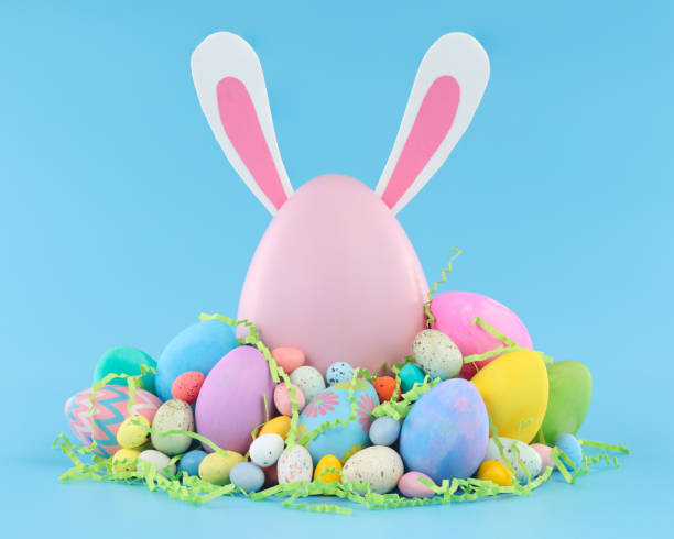 istock Large pink Easter egg with bunny ears surrounded by a pile of colorful Easter eggs and candy. 1308169080
