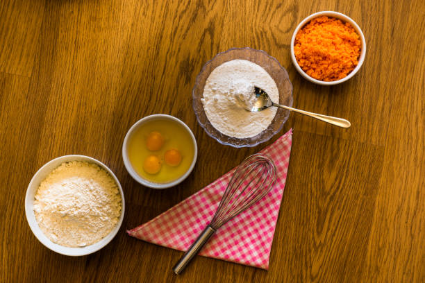 ingredients for carrot cake placed in bowls in a row on the diagonal of the shot