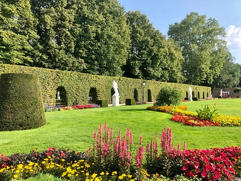 Trier, Germany - August 26, 2019: Palastgarten, the Palace Gardens in Trier, an elegant french style palace with garden, fountains, sculptures and flower beds