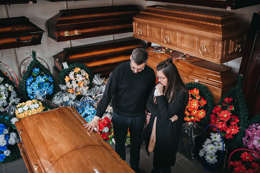 Undertaker showing coffins and crosses to a widow