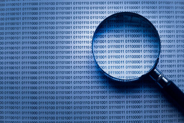istock Selective focus of magnifying glass on a paper sheet of binary code. 1308178725