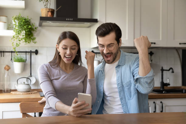 istock Excited couple feel euphoric with win on cellphones 1308180541