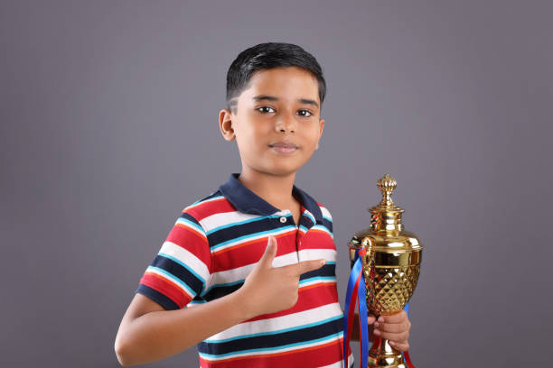 親指を立てながら黄金のトロフィーカップを持っているインドの男子生徒 - thumbs up child success winning ストックフォトと画像