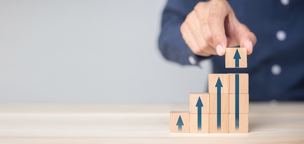 Growth graph and arrows ladder career path for business growth success process concept.Hand arranging wood block stacking as step stair with arrow up.