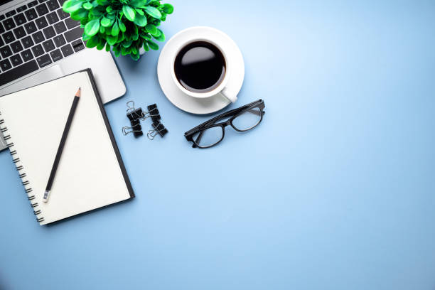 istock Flat lay, top view office table desk. Workspace with, laptop,office supplies, pencil, green leaf, and coffee cup on blue background. 1308193012