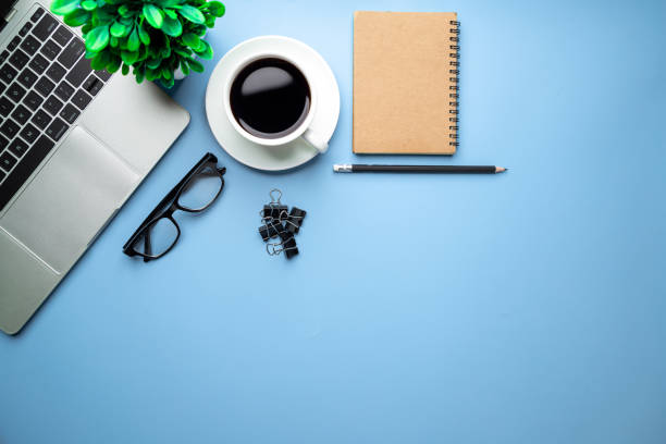 istock Flat lay, top view office table desk. Workspace with, laptop,office supplies, pencil, green leaf, and coffee cup on blue background. 1308193018