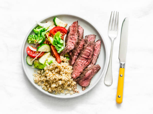 istock Balanced lunch - medium roast steak, vegetable salad and bulgur on a light background, top view 1308194663