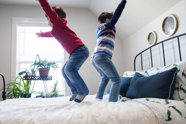 istock Adorable brothers jump on the bed while being mischievous 1308195654