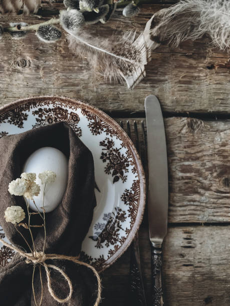 istock Stylish rustic Easter table setting. Natural egg, napkin, flowers, vintage plate, cutlery, feathers 1308199163