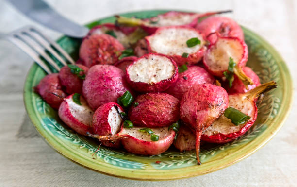 Baked radish with green onions. On the table on a plate baked radish with green onions and herbs. Presented in close-up. radish stock pictures, royalty-free photos & images