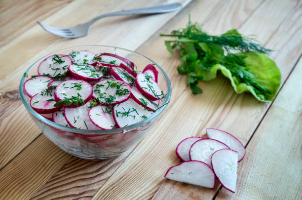 On the table sliced for salad radishes and herbs arugula.