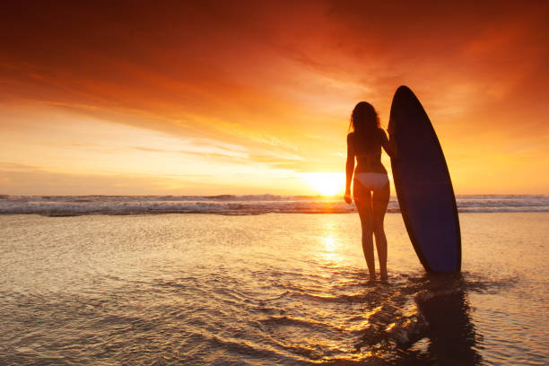 istock Woman holding surfboard at sunset 1308208100