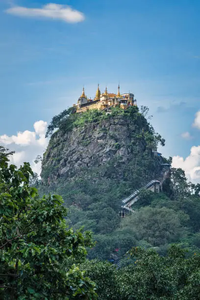Majestic Taung Kalat Buddhist Monastery on top of volcanic plug, which rises 657m (2156 ft) above the sea level. Long, steep wooden stairway climbing up to Taung Kalat (Pedestal Hill), Buddhist Pilgrimage Site, Mount Popa National Park, Bagan - Mandalay, Burma, Myanmar, Asia
