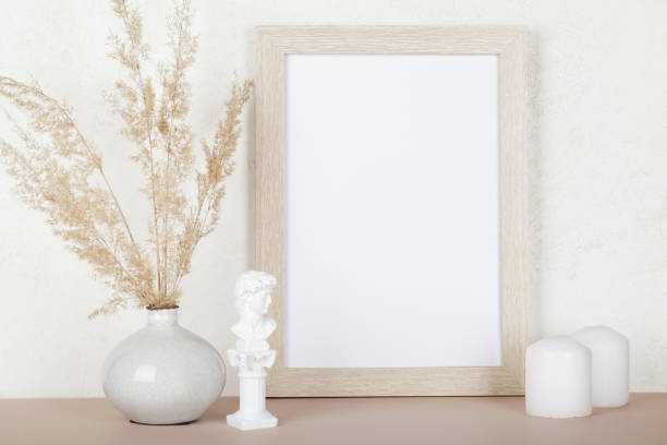 istock Portrait empty wooden frame mockup, dried pampas grass, small statue and candles on white background, interior, home design. Art concept. copy space. 1308208812