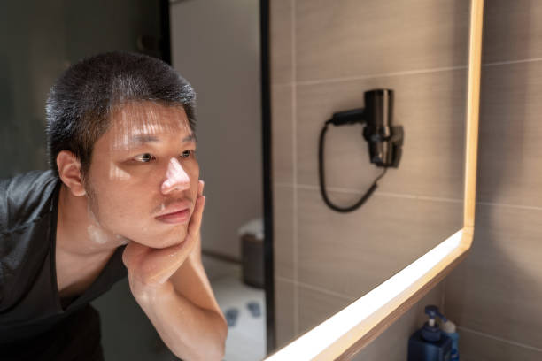 istock Young Asian man looking at himself washing his face in the mirror 1308210113