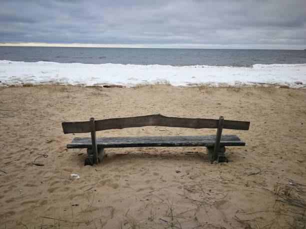 istock Old wooden bench on a sandy beach 1308213425
