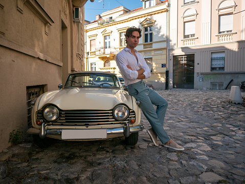 Portrait of young handsome guy. Bored and annoyed man on the street. vintage car
