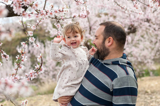 istock Father and daughter together under a blooming tree 1308216149