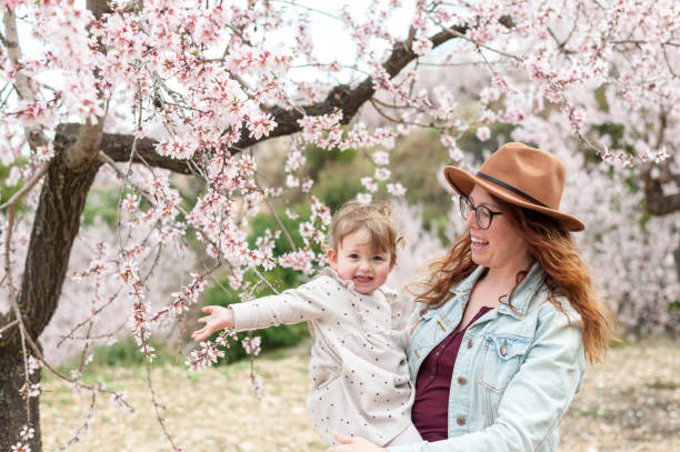 istock Mother and daughter pink almond tree 1308216173