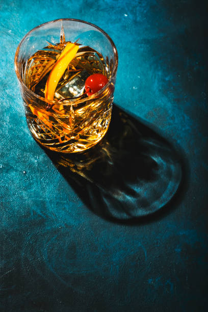 istock Old fashioned cocktail with bourbon whiskey, cherry and orange peel garnish, blue table, copy space, top view 1308217956