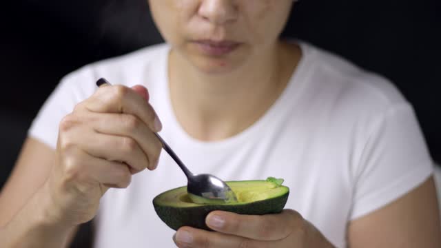 Woman eating Avocado with with spoon