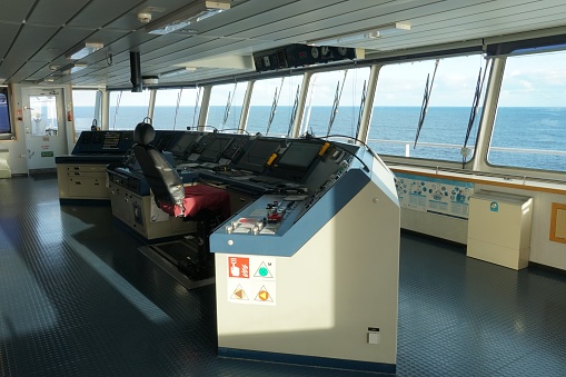 The Modern Ship’s Bridge control console with navigational equipment of container ship with view on the sea sailing through Pacific ocean.