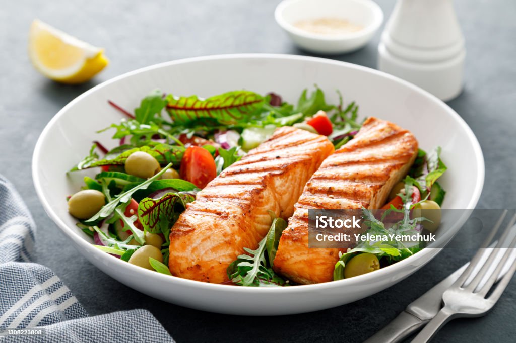 Grilled salmon fillet and fresh vegetable salad. Mediterranean diet. Salmon - Seafood Stock Photo