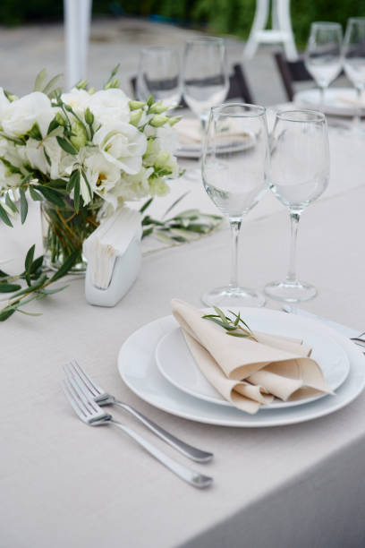 istock Table setting with beige napkin on empty white plate, wineglasses and cutlery on table, copy space. Place setting at wedding reception. Table served for banquet 1308226007