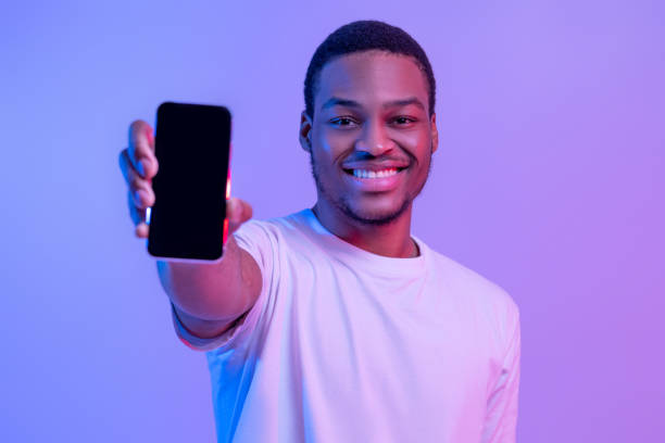 istock Handsome African American Guy Showing Smartphone With Black Blank Screen At Camera 1308227345