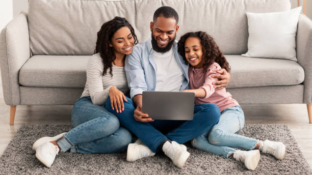 istock Happy black family using laptop sitting on the floor 1308227519