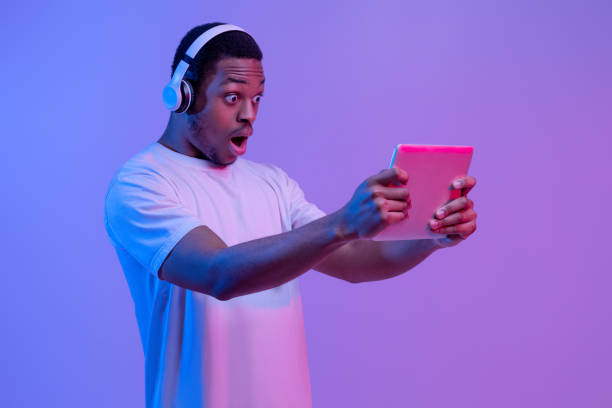 istock Cool Game. Excited African Man In Headphones Looking At Digital Tablet Screen 1308228159