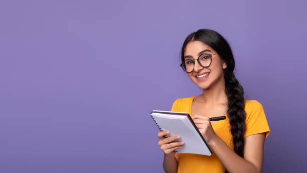 istock Indian woman holding pen writing in notebook at studio 1308228429