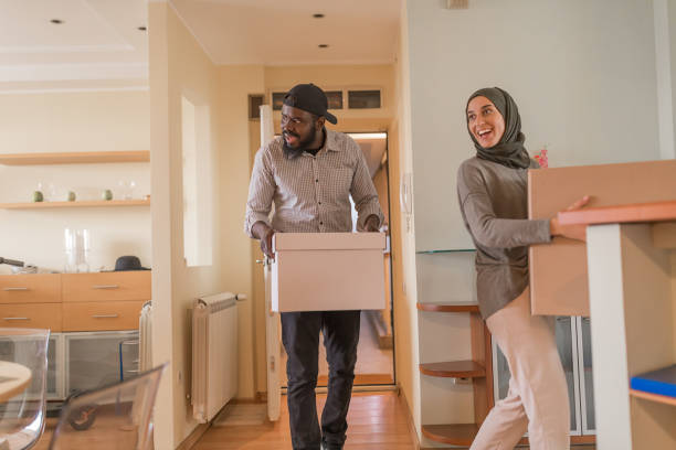 An Excited Young Multi-Ethnic Couple Carries Paper Boxes into the New Home.