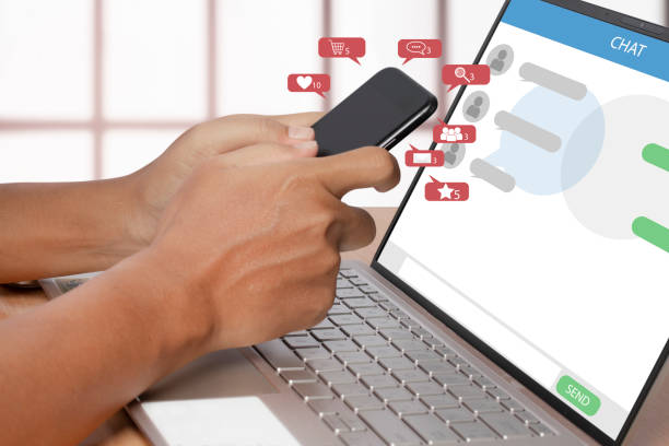 istock Social media on a smartphone with notification icon and computer laptop. a person using a smartphone in interior building. 1308229763