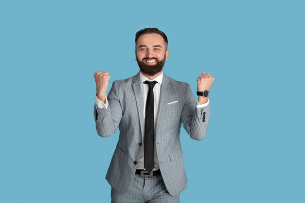istock Handsome young businessman feeling excited and gesturing YES on blue studio background 1308231059