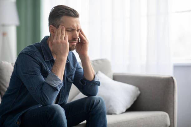 istock Stressed man having headache, sitting on sofa at home 1308231350