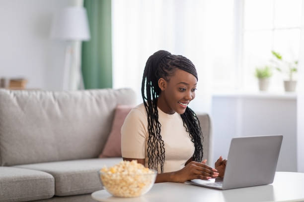 istock Young black lady choosing movie on laptop 1308231437