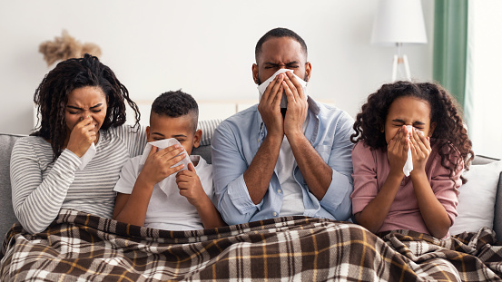 Familia negra enferma soplando narices mocosas con servilletas juntas photo