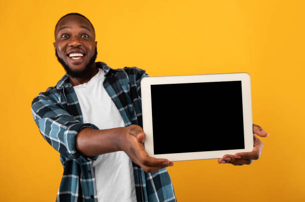 istock Joyful African Man Showing Empty Digital Tablet Screen, Yellow Background 1308231668