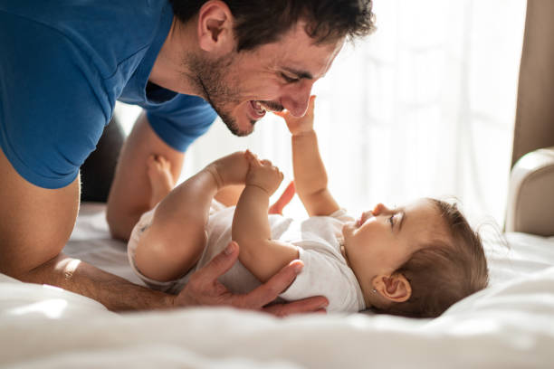 istock Father and baby playing on bed 1308232363