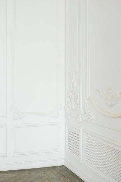 istock White walls with an elegant panel made using stucco moldings and wooden flooring in the corner of empty room, interior design elements. Home interior, empty room. Copy space. 1308234944