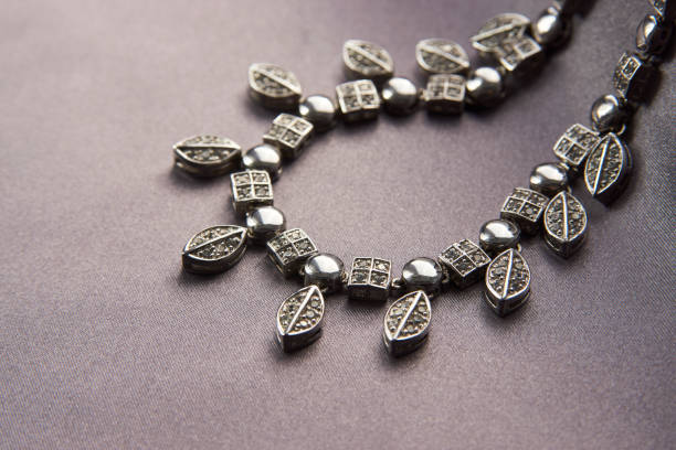 Elegant necklace with diamonds on grey background with copy space. Women's platinum necklace with a precious gemstones, close-up. Elegant female jewelry